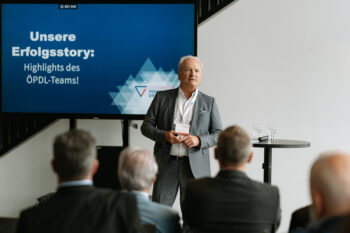 Mann steht auf der Bühne und spricht zum Publikum