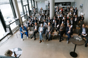 Menschen im Publikum halten einen Folder in die Luft