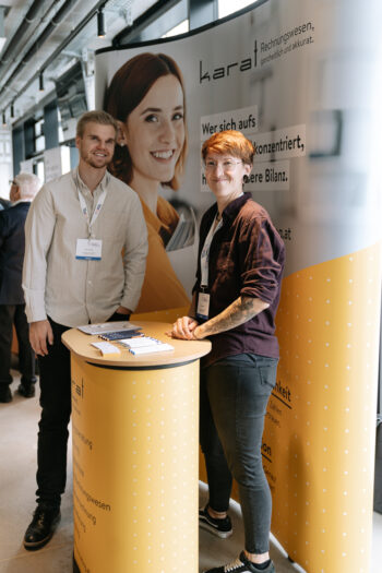 Zwei junge Menschen stehen an einem Messestand
